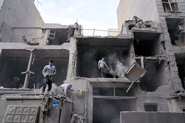 Volunteers clean debris from a residential building damaged when a nearby police station was hit Friday in a U.S.-Israeli strike in Tehran, Iran, Sunday, March 15, 2026.