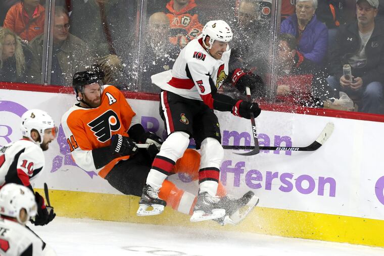 Flyers' forward Jori Lehtera (left) gets checked into the boards by Senators defenseman Cody Ceci during the Flyers' 4-3 loss on Tuesday.