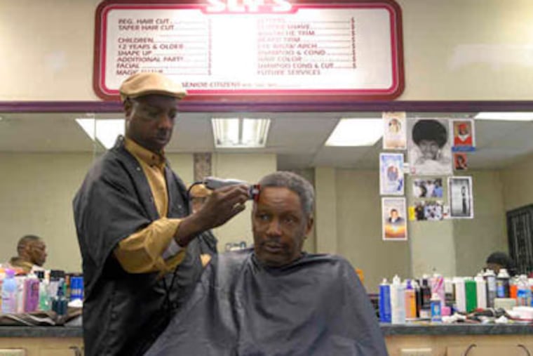 Ralph Jones, one of the new owners of Sly's Barbershop in Strawberry Mansion, cuts the hair of Steve James, a customer for 30 years. (Ron Tarver / Staff Photographer)