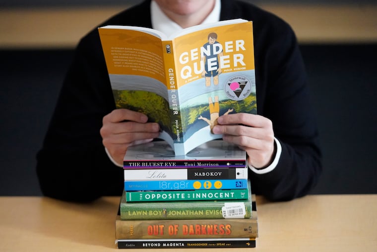 Amanda Darrow, director of youth, family and education programs at the Utah Pride Center, poses with books that have been the subject of complaints from parents in Salt Lake City on Dec. 16, 2021. The wave of attempted book banning and restrictions continues to intensify, the American Library Association reported Friday. Numbers for 2022 already approach last year's totals, which were the highest in decades.