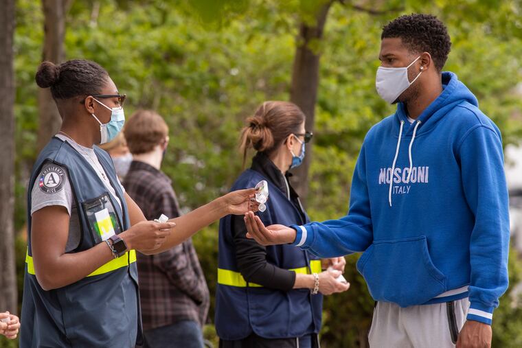 A young man receiving hand sanitizer before entering the Burlington County COVID-19 vaccination site at Moorestown Mall on Monday, the day the state opened vaccinations to ages 16 and older.