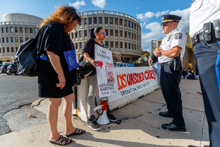 Roz Pichard (center) whose brother Alexander Martinez was murdered seven years ago, speaks with Philadelphia Police Captain Steve Clark on the 7th Street side of police headquarters. Families of unsolved murder case victims are conducting a three-day silent protest at the Roundhouse.