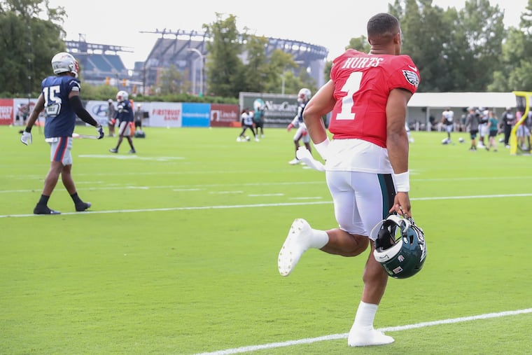With Lincoln Financial Field in the background, Jalen Hurts runs onto the field before a joint workout with the New England Patriots on Aug. 17.