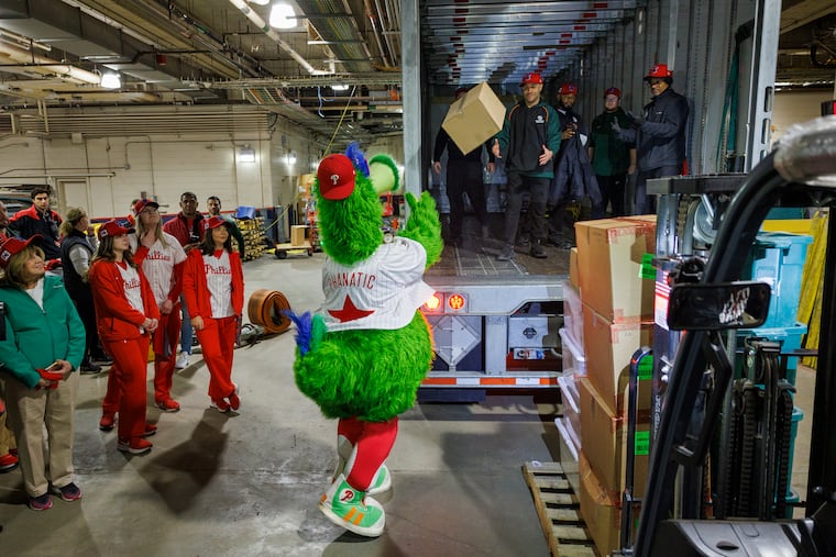 The Phanatic tosses a box onto one of the three trucks that were loaded up with equipment on Monday for the drive to the Phillies' spring training home in Clearwater, Fla.