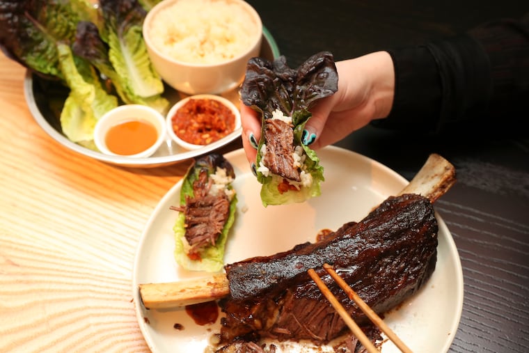 Assembling the bone-in beef short rib marinated in soy, asian pear, garlic, braised and grilled on the bone ssam platter served with lettuce, ssamjang sesame oil and steamed rice at Kpod in University City.