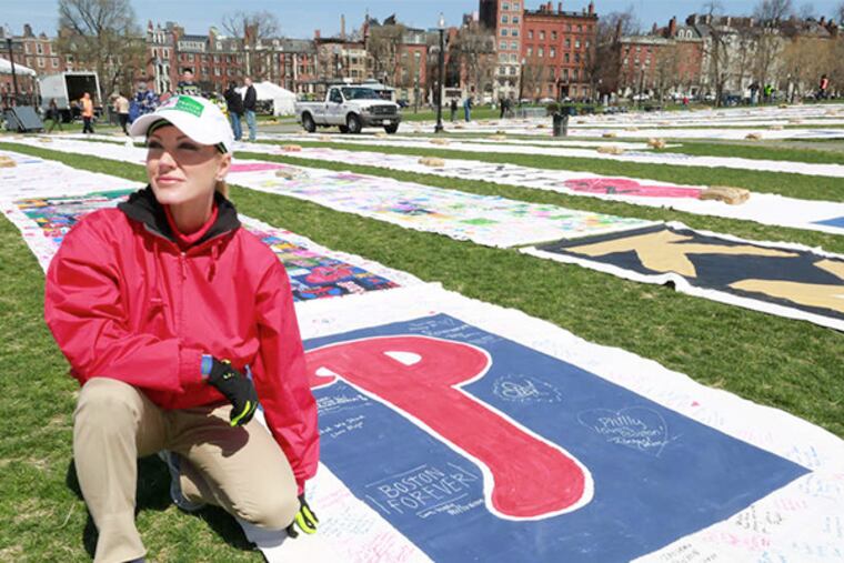 Kari Wagner, founder of America 4 Boston, kneels near a prayer canvas from Philadelphia, one of more than 200 sentby well-wishers from all over the country and unfurled on Boston Common. DAVID SWANSON / Staff Photographer