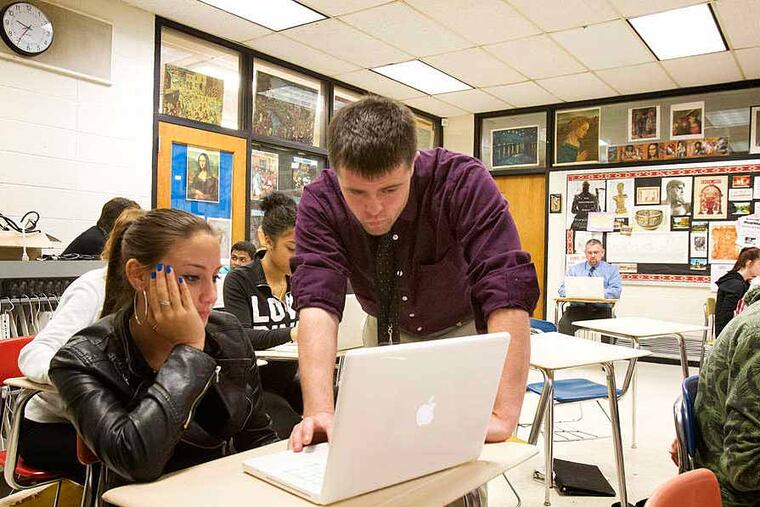 At Upper Darby High School, first-year teacher Joe Niagara works with senior Amanda Farina in class while Principal Christopher Dormer (seated, rear) observes and takes notes for Niagara's evaluation.
