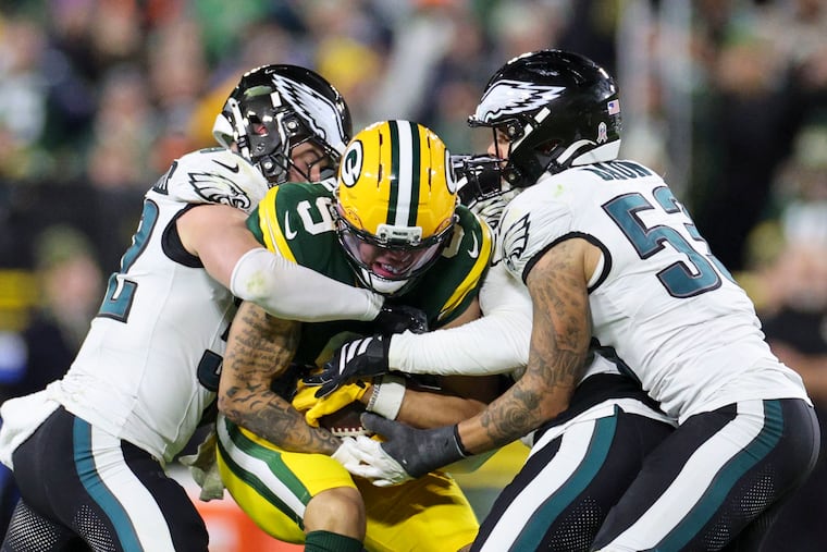 Eagles safety Reed Blankenship (left) and linebacker Zack Baun hit Green Bay's Christian Watson after a catch on Monday night.