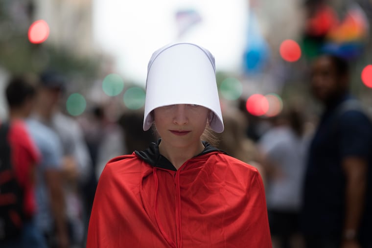 A woman protests on Broad Street for the pending arrival of Vice President Mike Pence at the Union League, in Philadelphia.