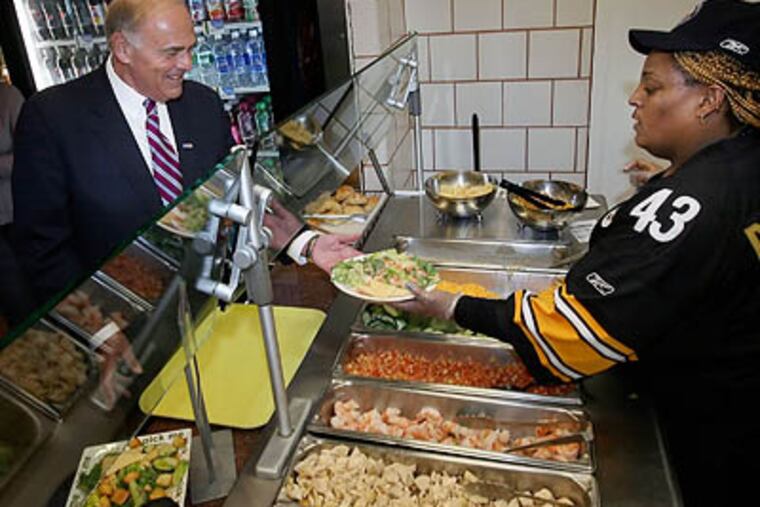 Amanda Robinson, right, hands over a shrimp Caesar salad as Governor Ed Rendell, eats lunch at the Capital Restaurant for the first time since it was closed for health violations, at the State Capitol in Harrisburg Friday. (AP Photo / The Patriot-News, Chris Knight)