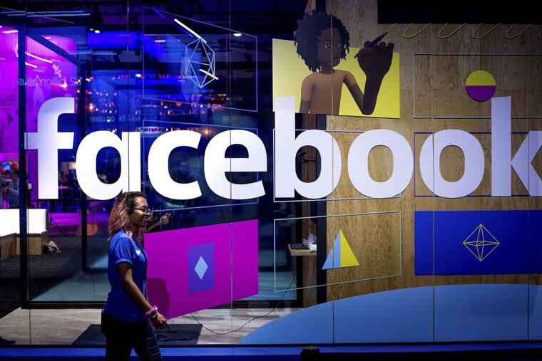 A conference worker passes a demo booth at Facebook’s annual F8 developer conference in San Jose, Calif.