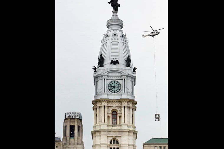 A helicopter lifts a P, the first letter removed from the south facing side of the PNB sign at 1 S. Broad St., and carries it past City Hall, August 17, 2014.