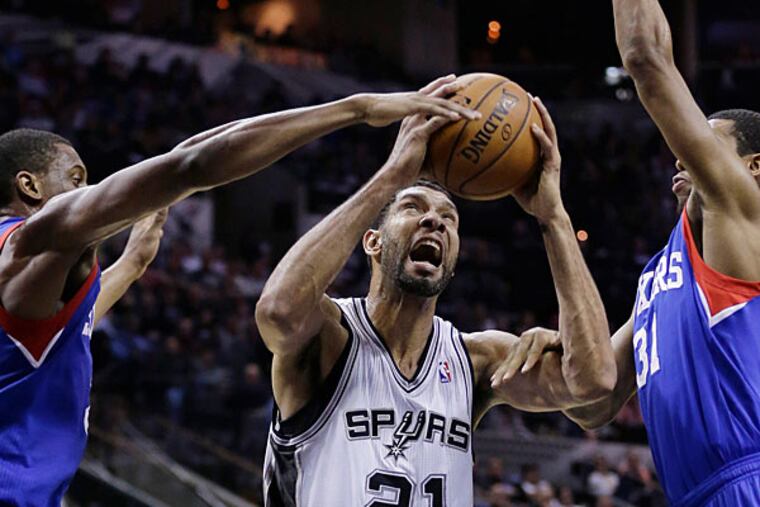 The Spurs' Tim Duncan is pressured by the 76ers' Thaddeus Young and Hollis Thompson during the first half. (Eric Gay/AP)