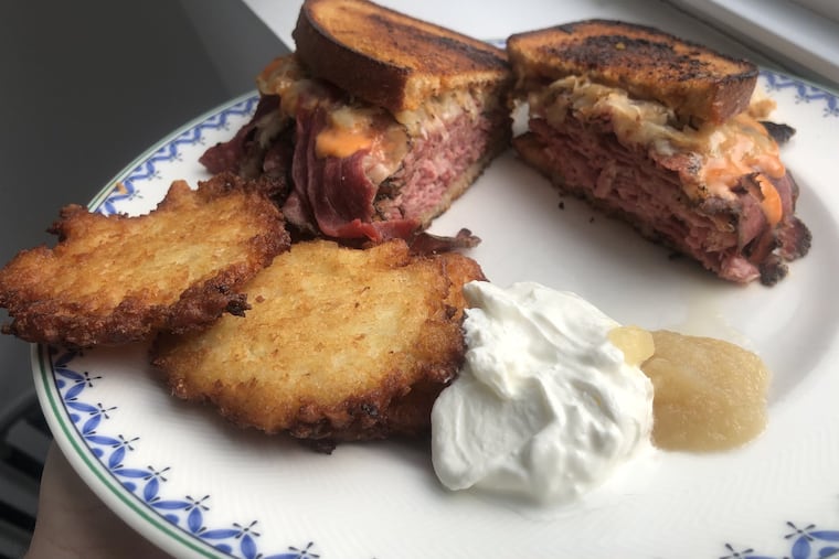 A corned beef and pastrami Reuben from Schlesinger's Deli, with a side of crispy potato pancakes.