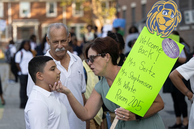 Yorkship School special education teacher Jennifer Seitz interacts with fourth grader Sergio Matir and his father, Jose Matir, as she welcomes them back on the first day of school in Camden on Friday.