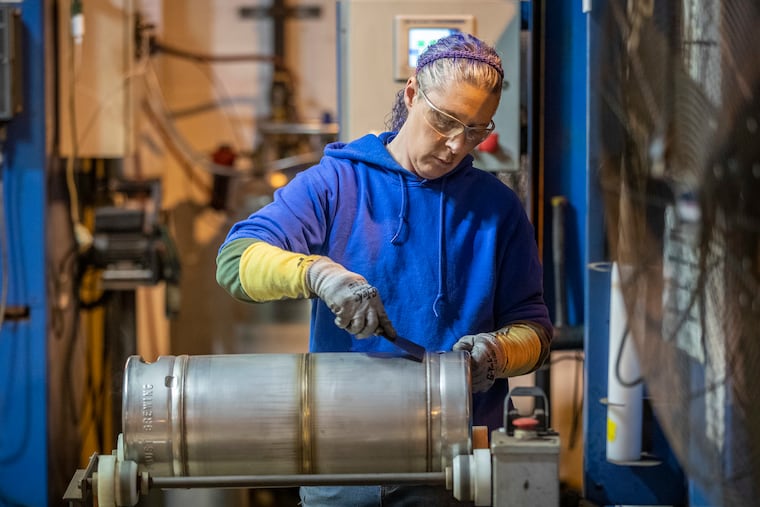 Pam Soulsby cleans the weld lines on a 1/6th barrel keg after the chimes, the top and bottom handles, were welded by an automated welding machine at American Keg in Pottstown.