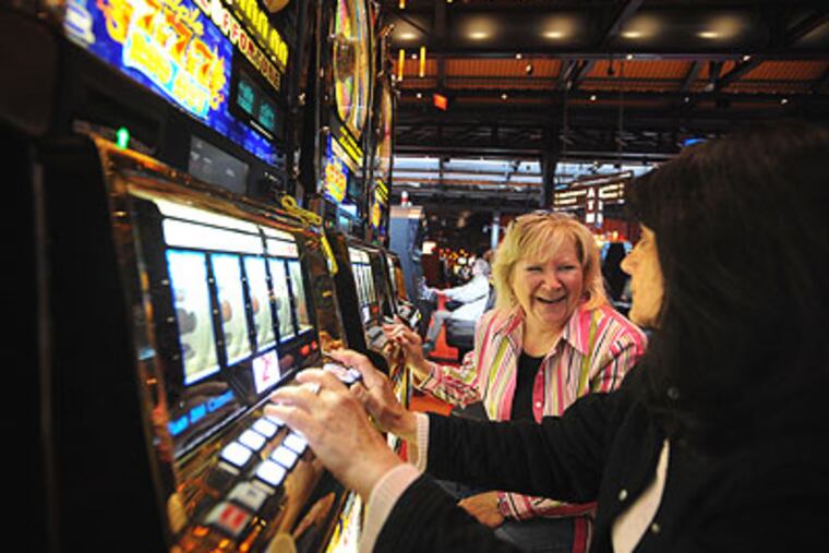 At the Sands Casino Resort in Bethlehem last month, Kathy Frey of Allentown (left), tells her friend Angela Brazzo of Hellertown, about her wins on the slots. Slow business prompted the casino to lay off 80 workers Friday. (Sharon Gekoski-Kimmel / Staff Photographer)