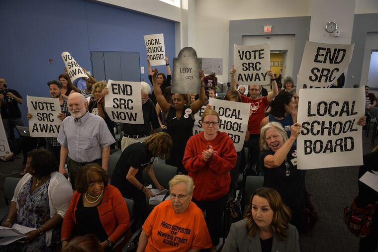 Parents, teachers, and education activists shout and hold signs calling for the end of the School Reform Commission last month. The SRC voted to revoke Khepera’s operating agreement for financial and academic failures.