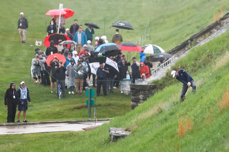 The fans' umbrellas were put to work as Keegan Bradley hit his second shot from a hill to the 17th green on Friday.
