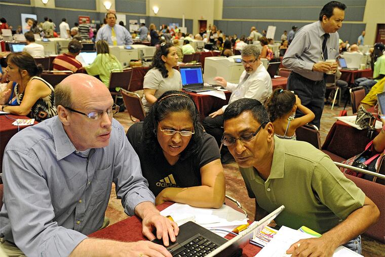 Jignasha Shah (center), 45, and her friend and fellow Revel Hotel and Casion housekeeper Ranjitsinh Rana (right), 56, both from Galloway Township, lean in as Unite Here Local 54 union rep John McCaffery, Queens, NY, explains unemployment benefits at the Atlantic City Convention Center Sept. 3, 2014. The union and the NJ Dept. of Labor organized the gathering to help unemployed casino workers get benefits. (Clem Murray / Staff Photographer)