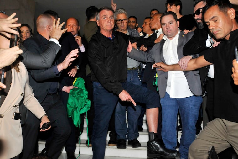 Brazil's former President Jair Bolsonaro points to his electronic ankle monitor that the Supreme Court ordered him to wear on July 21.