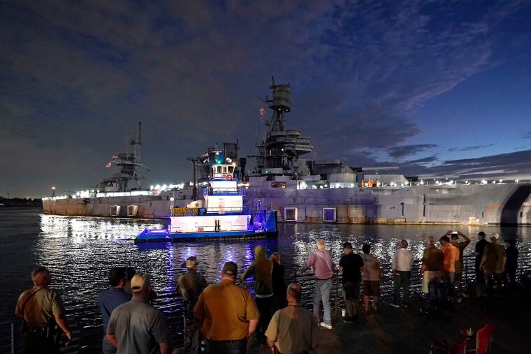 People watch as the USS Texas is moved from the dock Wednesday in La Porte, Texas.