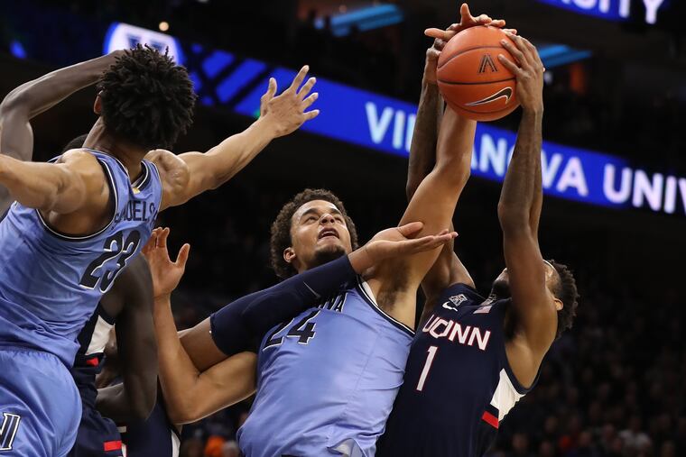 Jeremiah Robinson-Earl (center) of Villanova battles for a rebound with teammate Jermaine Samuels and Christian Vital of Connecticut at the Wells Fargo Center.