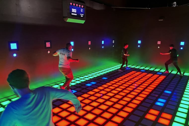 Jason Shacket, from left, Robert Cole, and Christina Schmidbauer play a game of "Mega Grid," similar to the childhood game, "The Floor Is Lava," commonly played on living room furniture and cushions. Activate Gaming in Cherry Hill takes that concept and brings it into an LED floor for even more complexity. It's set to open in late November 2025.