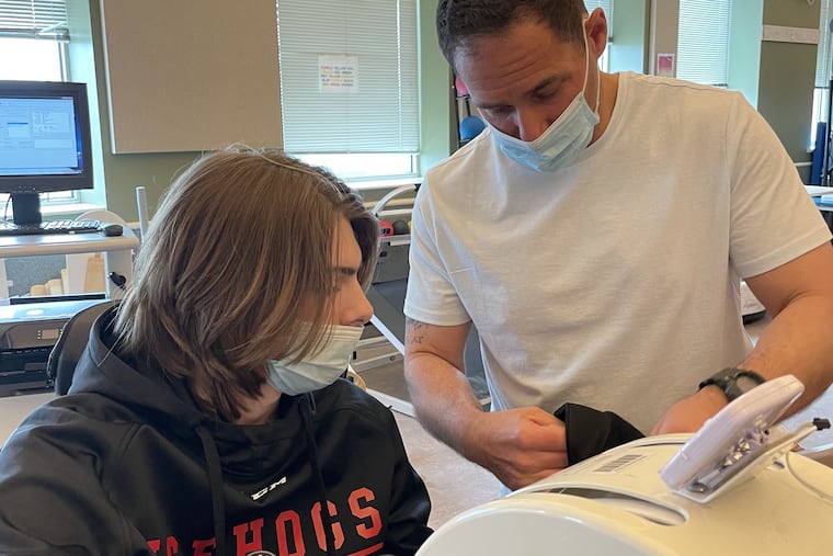 Brian Page (left) works on his cardio while using an arm bike at Magee Hospital. The Little Flyers hockey player was paralyzed during a game in November.