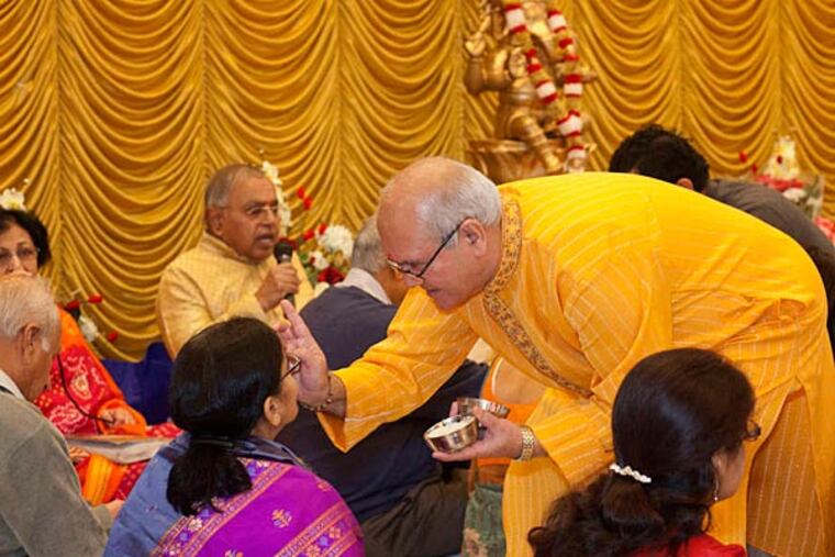 Ghanshyam Dave applies the tikka symbol to a woman at Sunday's ceremony . ED HILLE / Staff Photographer
