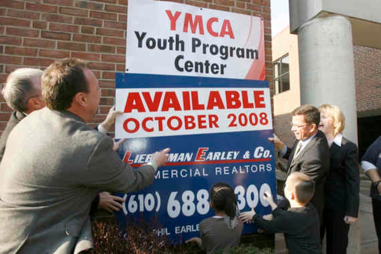 YMCA officials take down the "for sale" sign at the facility in downtown West Chester. They have decided to not sell it and will offer more youth programs there. Some had opposed relocation to East Goshen.
