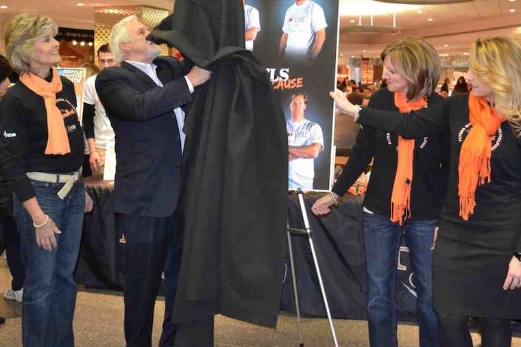 Bernie Parent unmasks the program cover for the Flyers Wives Fight for Lives Carnival in the Comcast Center's food court. With the Hall of Fame goaltender Wednesday were (from left) Doreen Holmgren, wife of general manager Paul Holmgren; Elaine Reese, wife of goalie coach Jeff Reese; and Lisa Hanrahan, wife of assistant general manager Barry Hanrahan. The carnival will be held Feb. 27 at the Wells Fargo Center.
