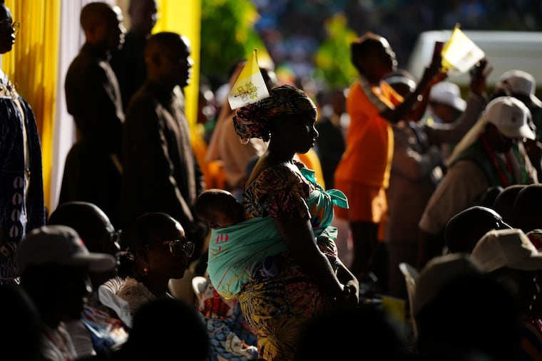 A woman with her child attends Pope Leo XIV's meeting with students and professors Friday at the Catholic University of Central Africa in Yaounde, Cameroon.