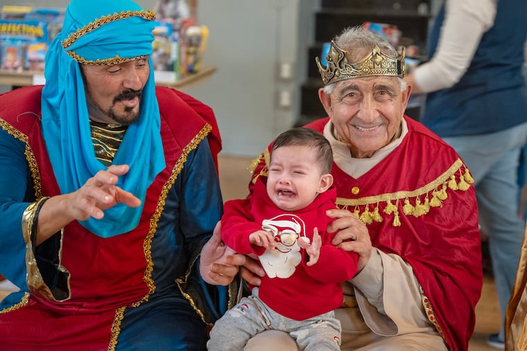 Two of the Three Kings, Luis Quinones and Joseph Incandela (right) pose with a reluctant one year-old Uriel as his mother Odele Rodrigues tries to take a photo.
