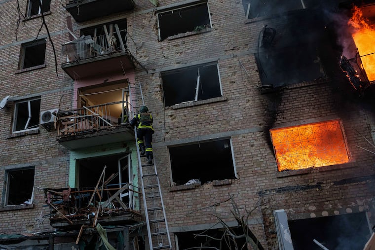 A rescue worker climbs on a ladder to help evacuate people from a residential building destroyed after a Russian strike on Kyiv, Ukraine, Sunday, May 24, 2026.