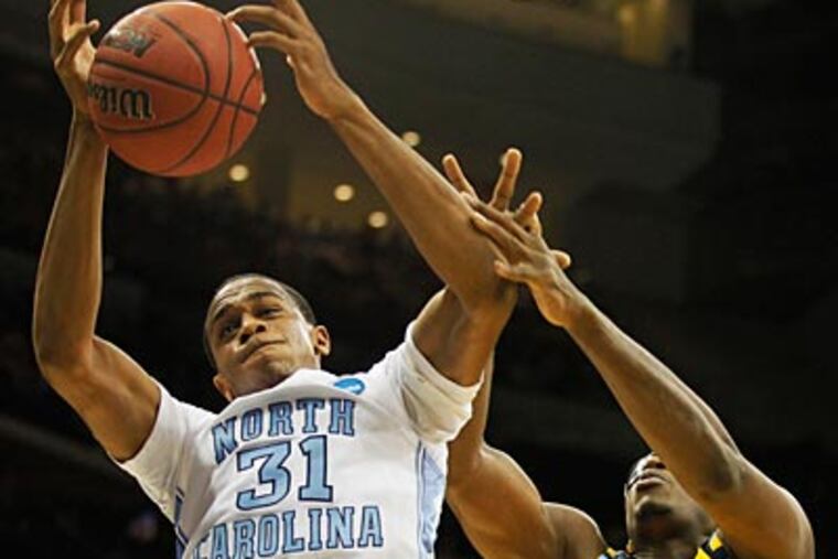 North Carolina's John Henson drives past Marquette's Chris Otule during the first half. (Julio Cortez/AP Photo)