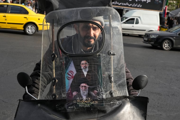 A man drives his motorbike Monday in Tehran with a poster on its windshield depicting Iran's Supreme Leader Ayatollah Mojtaba Khamenei, top, and his father, the slain Supreme Leader Ayatollah Ali Khamenei, who was killed in the U.S. and Israel strikes on Feb. 28.