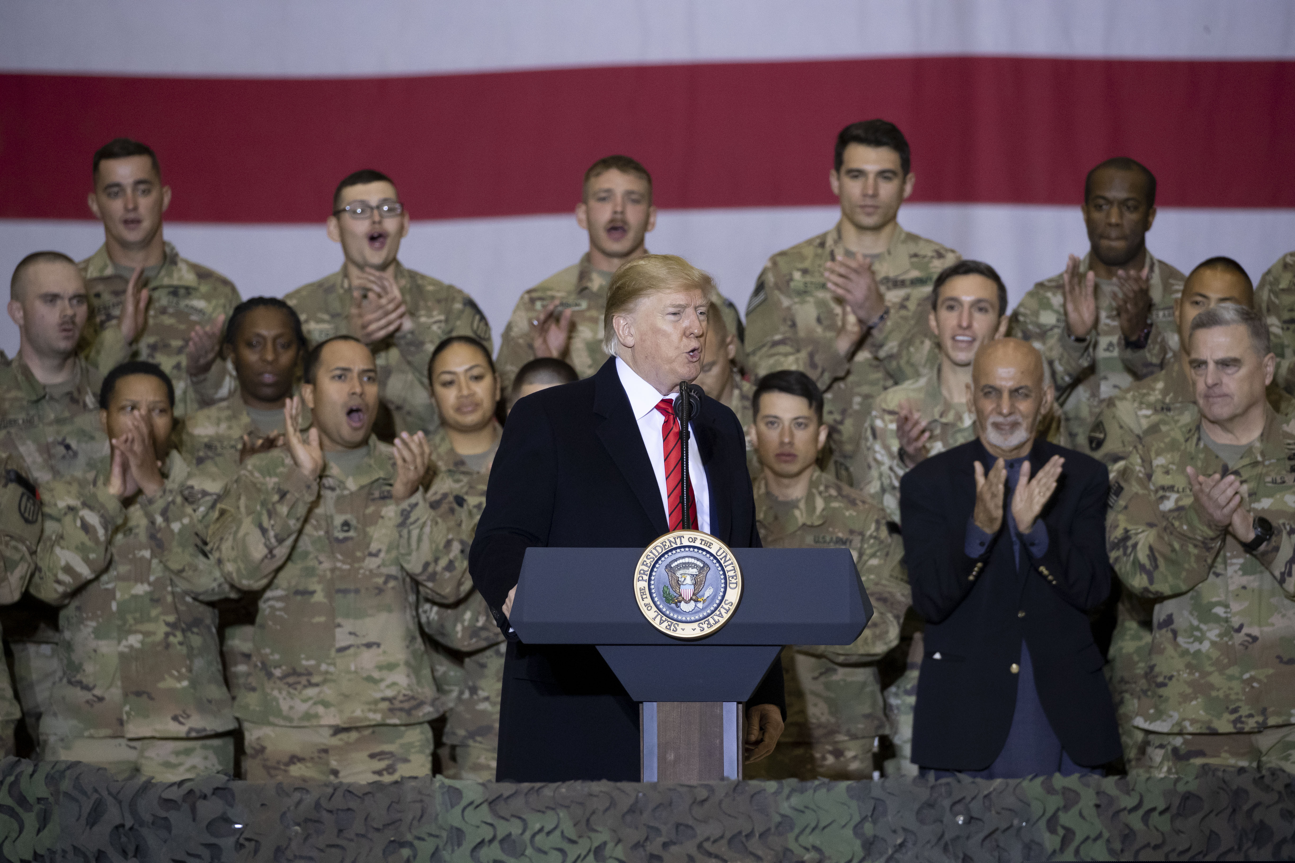 President Donald Trump, center, with Afghan President Ashraf Ghani, second from the right, and Joint Chiefs Chairman Gen. Mark Milley, right, while addressing members of the military during a surprise Thanksgiving Day visit, Thursday, Nov. 28, 2019, at Bagram Air Field, Afghanistan.