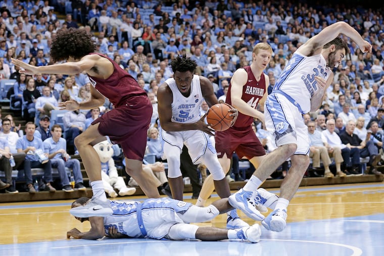 North Carolina's Nassir Little (5) grabs the ball while Kenny Williams falls and tangles with Luke Maye (32) during a play against Harvard's Mason Forbes and Henry Welsh (44) during the second half of an NCAA college basketball game in Chapel Hill, N.C., Wednesday, Jan. 2, 2019. (AP Photo/Gerry Broome)