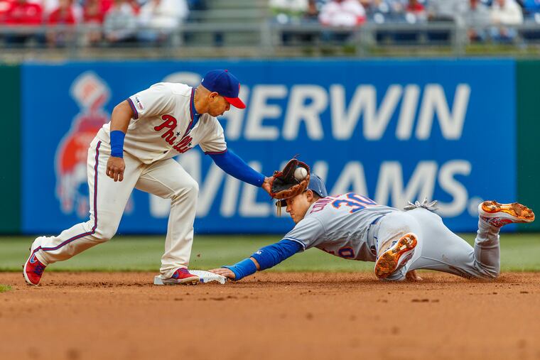 Phillies second baseman Cesar Hernandez, left, reaches to tag New York Met Michael Conforto, right, who stole second in the second inning of their game on April 17, 2019.