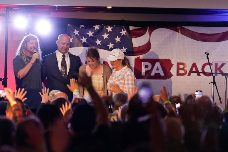 Doug Mastriano, on stage with Sean Feucht, left, his wife Rebbie and Jenna Ellis, right, take part in a primary night election gathering in Chambersburg in May 2022. His general election campaign has been turbulent.