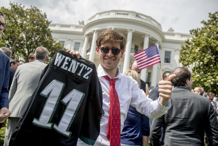 Tim Dagit of Chester Springs, Pa. holds up a Philadelphia Eagles jersey for quarterback Carson Wentz and an American flag during the "Celebration of America" event on the South Lawn of the White House, Tuesday, June 5, 2018, in Washington. Trump quickly scheduled the event with military bands after canceling a visit with the Philadelphia Eagles as he stoked fresh controversy over players who protest racial injustice by taking a knee during the national anthem. (AP Photo/Andrew Harnik)