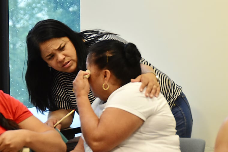 Milagros Barreto, an organizer at the Massachusett Coalition for Occupational Safety and Health (MassCOSH), consoles a member of MassCOSH's Immigrant Worker Center at a 2018 meeting in Boston.