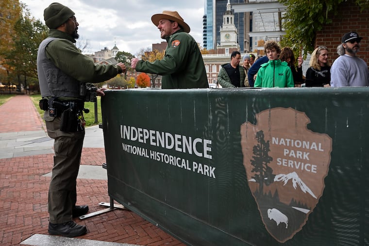 National Park Service law enforcement ranger Johan Urena (left) greets park ranger John Dunlap (right) as visitors line up outside the Liberty Bell Center in Independence National Historical Park on Thursday, Nov. 13, as the federal government returned to work from the shutdown. Urena and other law enforcement rangers worked through the shutdown, while this was the first day back for Dunlap and his fellow rangers.