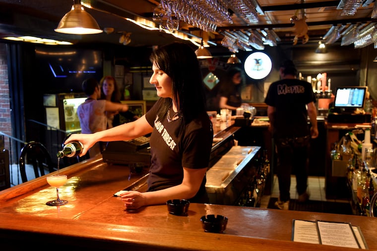 Bre Dunn , bartender pours a drink at the bar, 12 Steps Down, at 9th & Christian Streets.
