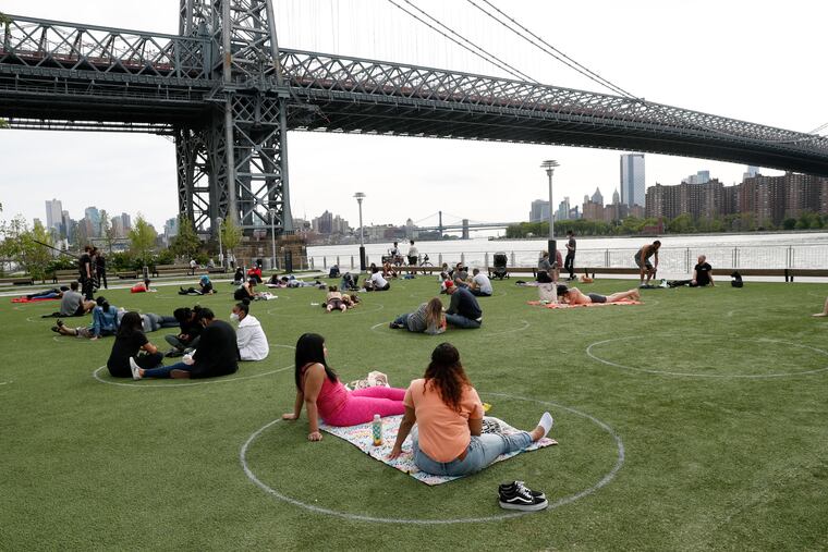 People relax in circles marked on the grass for proper social distancing at Brooklyn's Domino Park during the current coronavirus outbreak, Monday, May 18, 2020, in New York.