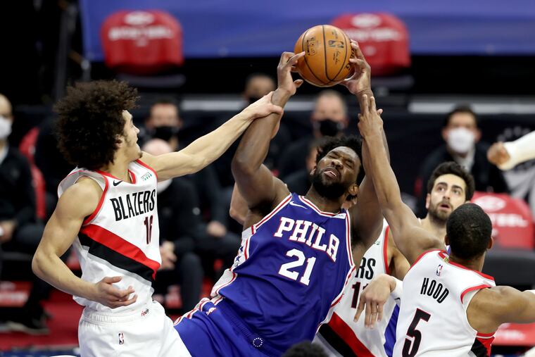 Joel Embiid gets fouled by CJ Elleby, left, as he goes after a rebound.