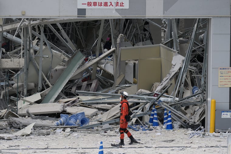 A rescue worker walks in front of AEON Mall, which was damaged by an explosion following an earthquake, is seen in Kashima, Kumamoto Prefecture, southern Japan, Wednesday, July 29, 2026. (AP Photo/Hiro Komae)