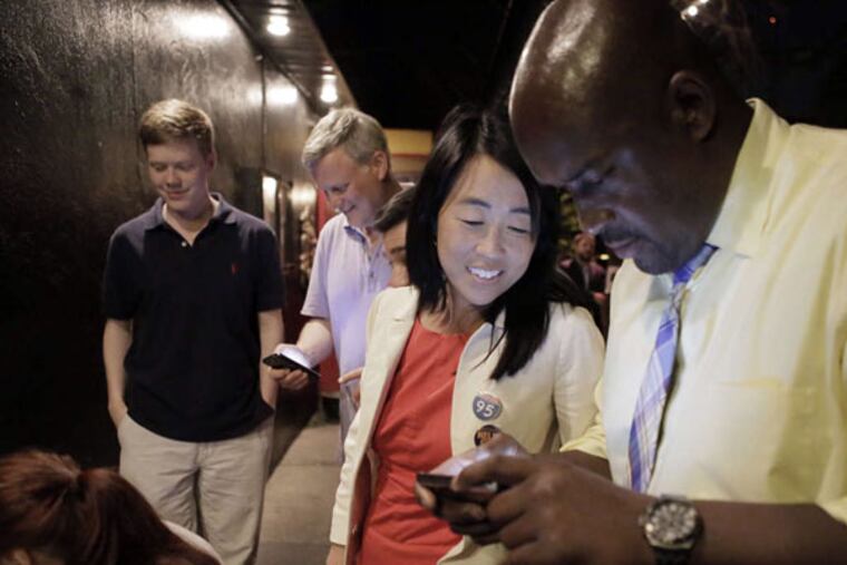 Helen Gym looks at election results with Antione Little of Philadelphia at the Belgian Cafe. (ELIZABETH ROBERTSON/Staff Photographer)