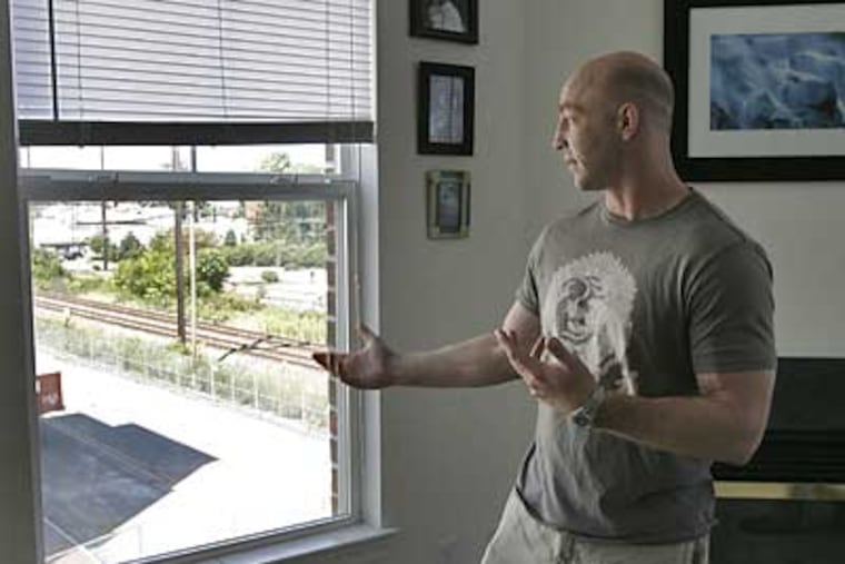 Preston Moritz looks out at a burned apartment from his window. Some tenants of the Riverwalk at Millennium complex were allowed back into their homes on Sunday. (Akira Suwa / Inquirer)